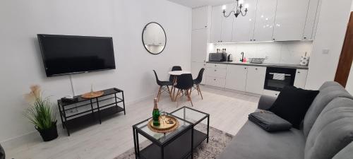 ein Wohnzimmer mit einem Sofa und einem TV sowie eine Küche in der Unterkunft 20 - Apartamenty Siedlce - Nowy apartament przy ul Lewandowskiego in Siedlce