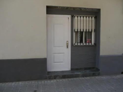 a white door on a building with a barred window at Cozy Rooms - BAÑERA HIDROMASAJE in Valencia