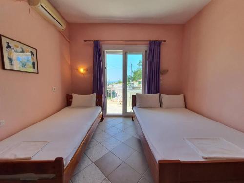 two beds in a room with a window at Studios Kyriaki in Limenaria