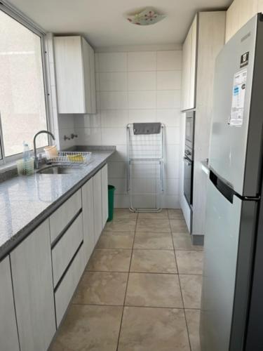 a kitchen with white appliances and a tile floor at Condominio Costa Peñuelas in Coquimbo