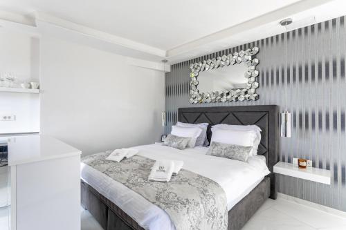 a white bedroom with a large bed and a mirror at Vidikovac Levanda Luxury Apartments in Hvar