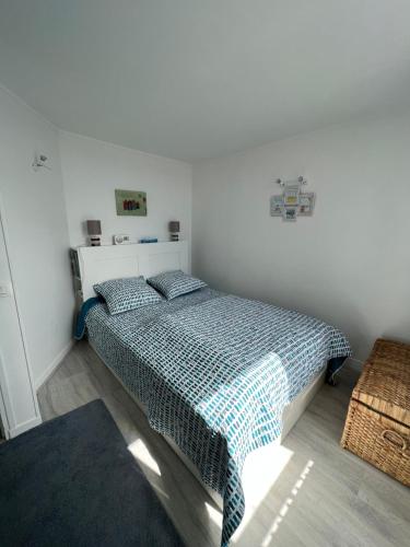 een slaapkamer met een bed met een blauw en wit dekbed bij Le Cocooning T2 rénové et 5min à pied de la mer au cœur de Trouville in Trouville-sur-Mer