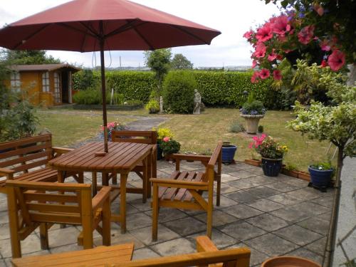 a wooden table and chairs with an umbrella at Meare Manor in Glastonbury