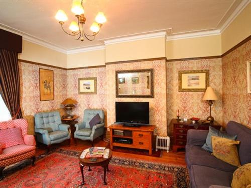 a living room with a couch and a tv at Meare Manor in Glastonbury