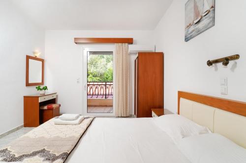 a white bedroom with a bed and a window at Apollonio in Chrysi Ammoudia