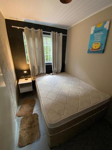 een kleine slaapkamer met een bed en een raam bij Casa Aconchegante próximo ao Capivari in Campos do Jordão