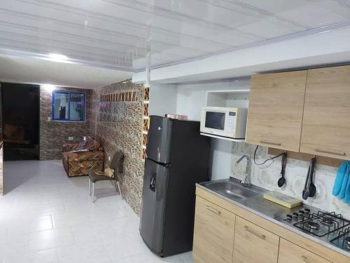 een keuken met een zwarte koelkast en een magnetron bij La Casa de La Piedra in Guatapé