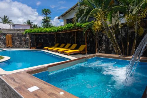 una piscina con sillas y una fuente de agua en Hotel Las Ninfas, en Puerto Ayora