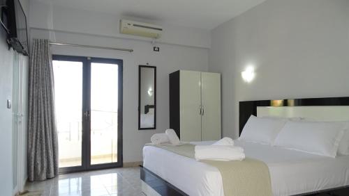 a bedroom with a large white bed and a window at Hotel Ardiani in Ksamil