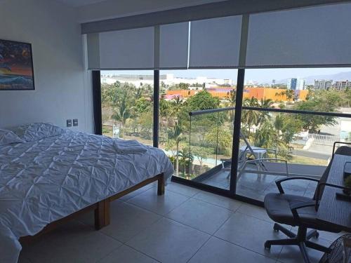 a bedroom with a bed and a chair and a large window at Altamar. Lugar perfecto para ser diamante in Acapulco