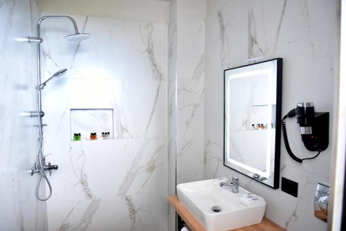 a white bathroom with a sink and a shower at Gogo's Boutique Hotel in Dhërmi