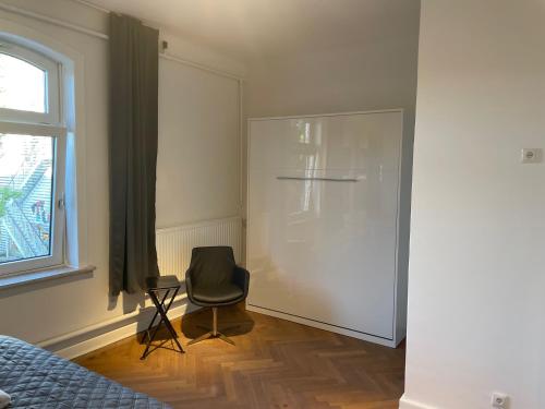 a bedroom with a chair and a refrigerator at Apartment Factory in Hamburg