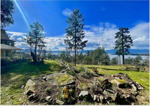 a rock wall in a yard with a rainbow in the sky at Quarrystone House B&B in Fernwood