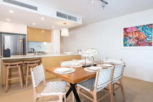 a kitchen and dining room with a wooden table and chairs at Darwin Waterfront Luxury Suites in Darwin