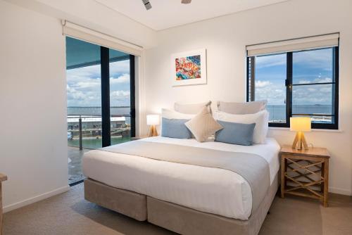 a bedroom with a large bed with large windows at Darwin Waterfront Luxury Suites in Darwin