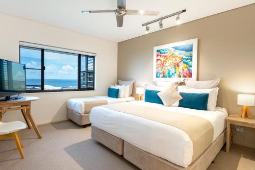 a bedroom with two beds and a flat screen tv at Darwin Waterfront Luxury Suites in Darwin