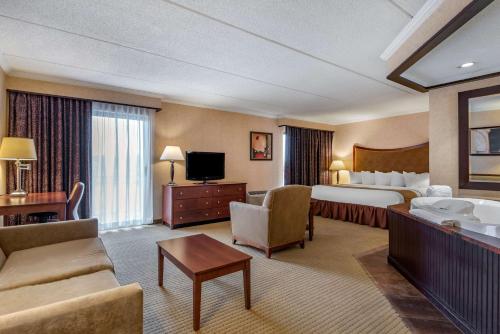 a hotel room with a bed and a living room at Best Western Plus Oswego Hotel and Conference Center in Oswego