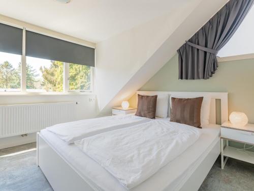ein weißes Schlafzimmer mit einem großen weißen Bett und Fenstern in der Unterkunft Tiny Zwarte Mees in Hulshorst
