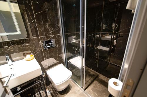 a bathroom with a shower and a toilet and a sink at Sea Palm Otel Yalıkavak in Yalıkavak