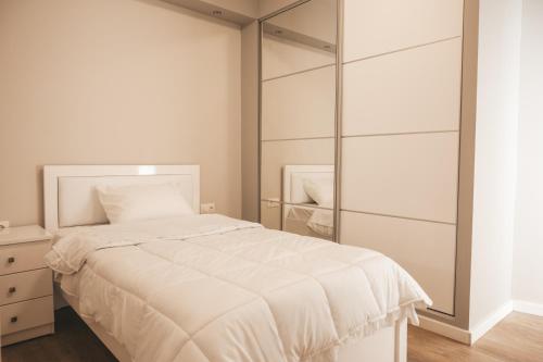 1 dormitorio con cama blanca y armario de cristal en Lovely apartment with balcony in the city center, en Katerini