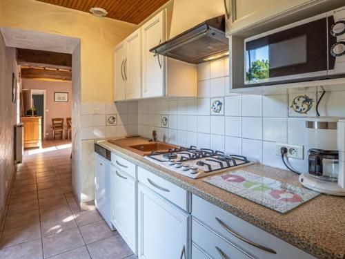 une cuisine avec des armoires blanches et un four à plaques de cuisson dans l'établissement Maison de ferme rénovée avec cheminée, terrasse et jardin clos - à 800m du bourg de Froidfond - FR-1-426-149, à Froidfond