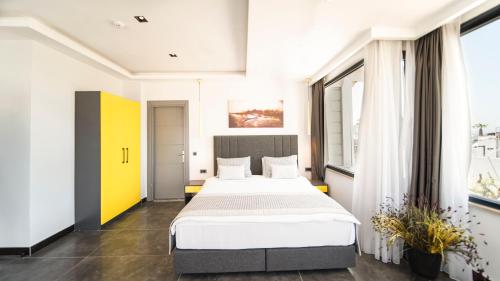 a bedroom with a large bed in a room with windows at Sea Palm Otel Yalıkavak in Yalıkavak