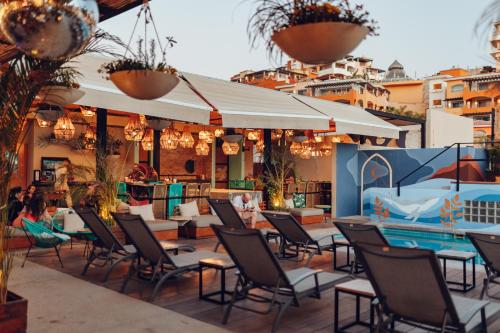 a patio with tables and chairs and a swimming pool at Mayan Monkey Los Cabos in Cabo San Lucas