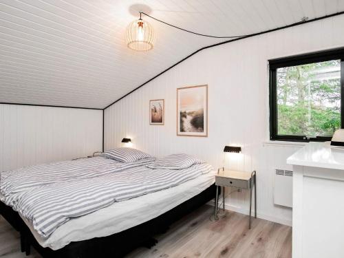 um quarto branco com uma cama e uma janela em Holiday home Ålbæk LXXXV em Ålbæk
