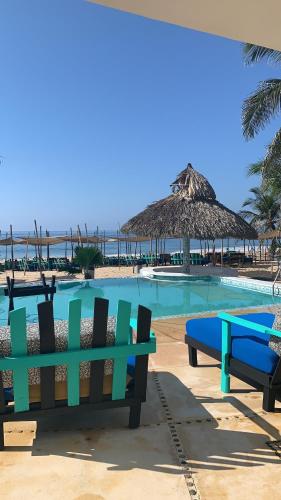 - une piscine avec 2 bancs et un parasol dans l'établissement Condominio Agave del Mar, à Coyuca