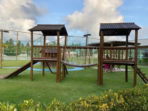 einen Spielplatz mit zwei Schaukeln und einer Rutsche in der Unterkunft Flat Garden 113 Muro Alto Condominio Clube in Porto De Galinhas