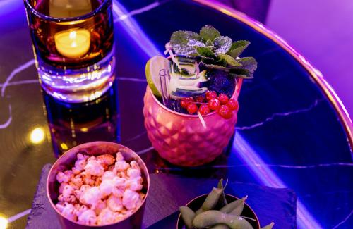 a glass table with a bowl of popcorn and a drink at Leonardo Hotel Augsburg in Augsburg