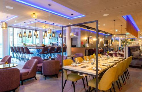 a restaurant with tables and chairs and a bar at Leonardo Hotel Augsburg in Augsburg