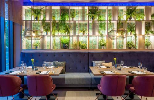 a restaurant with tables and chairs and a large window at Leonardo Hotel Augsburg in Augsburg