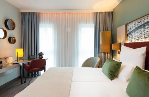 a hotel room with a bed and a desk at Leonardo Hotel Augsburg in Augsburg