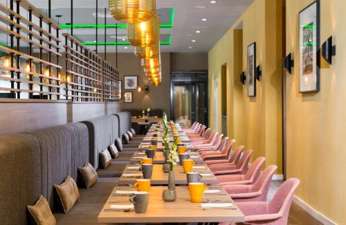 a long row of tables in a restaurant with chairs at Leonardo Hotel Offenbach Frankfurt in Offenbach