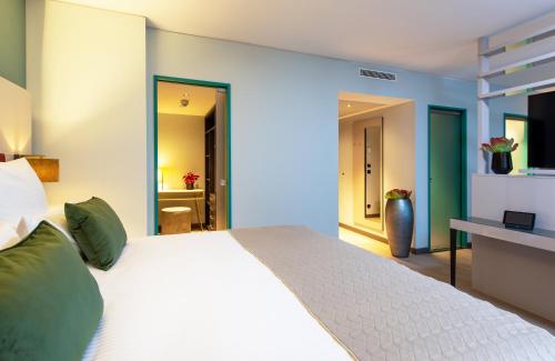 a bedroom with a large white bed with green pillows at Leonardo Hotel Augsburg in Augsburg