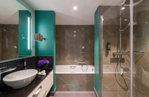 a bathroom with a sink and a shower at Leonardo Hotel Augsburg in Augsburg