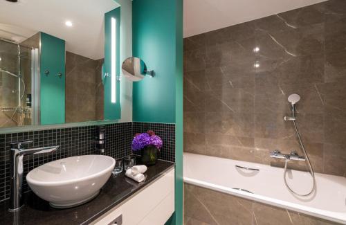 a bathroom with a sink and a bath tub at Leonardo Hotel Augsburg in Augsburg