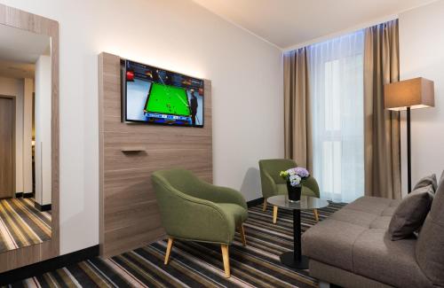 a living room with a couch and a tv at Leonardo Hotel Offenbach Frankfurt in Offenbach