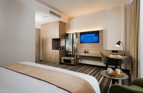 a hotel room with a bed and a tv at Leonardo Hotel Offenbach Frankfurt in Offenbach