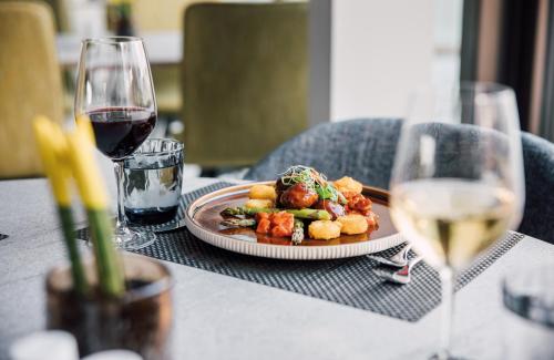 a plate of food on a table with a glass of wine at Leonardo Hotel Zurich Airport in Kloten