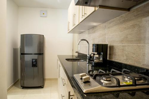 a kitchen with a sink and a refrigerator in it at Hotel Casa Alom in Cali