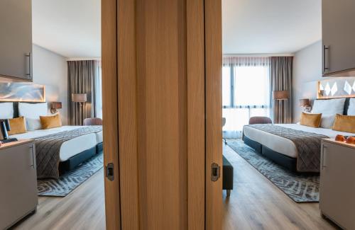 a hotel room with two beds and a window at Leonardo Royal Hotel Barcelona Fira in Barcelona
