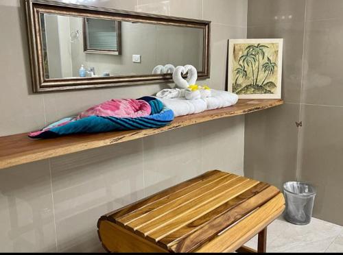 a bathroom with a shelf with towels and a mirror at Castara Inn in Castara