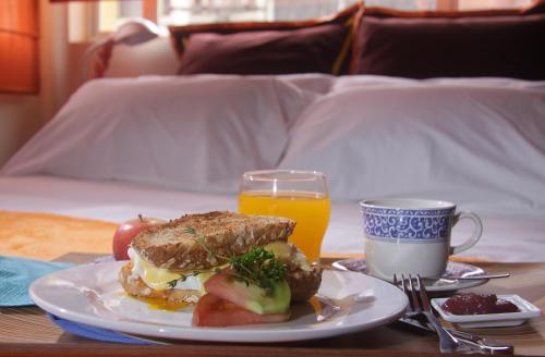 6 Suites Hotel في بوغوتا: ساندويتش على لوحة على طاولة مع كوب من عصير البرتقال