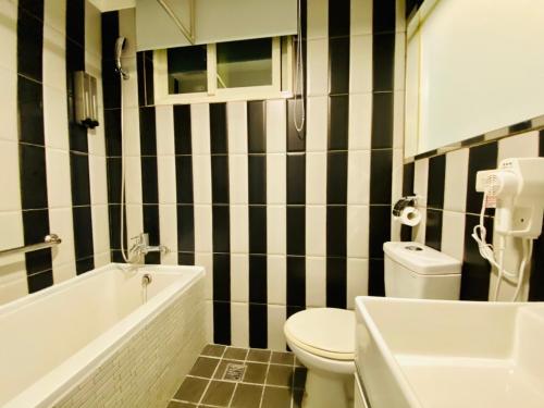 a black and white bathroom with a toilet and a sink at Hub Hotel Ximen Inn in Taipei