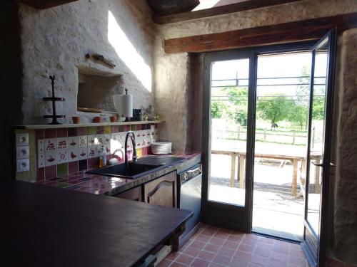 une cuisine avec un évier et une porte ouverte dans l'établissement Manor in Cotentin with Historic Charm, à Saint-Lo-dʼOurville