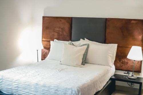 Schlafzimmer mit einem Bett mit weißer Bettwäsche und Kissen in der Unterkunft ARMONIA 408 APARTMENT IN GAZCUE in Santo Domingo