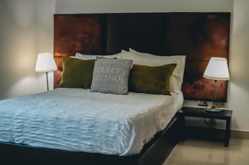 Una cama con dos lámparas y una almohada. en ARMONIA 408 APARTMENT IN GAZCUE, en Santo Domingo