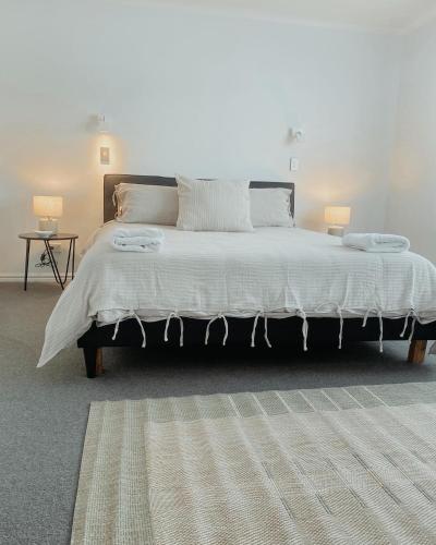a bedroom with a large white bed with two lamps at Sea Breeze 3 bedroom Apartment Mount Maunganui in Mount Maunganui